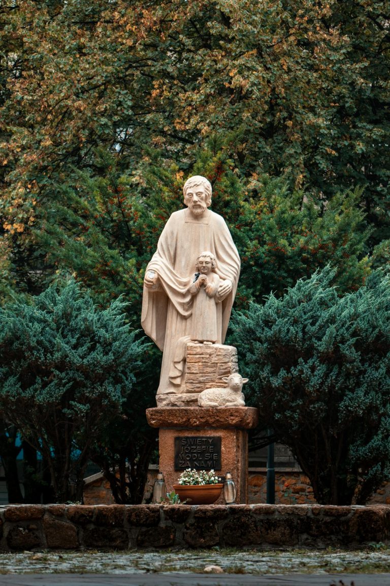 Sculpture of St. Joseph with child in a serene outdoor setting in Olkusz, Poland.
